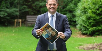 Minister Richmond holding the 2025 Irish Aid Annual Report in the gardens of Iveagh House.