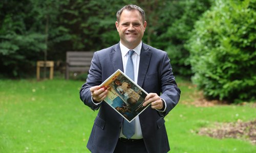 Minister Richmond holding the 2025 Irish Aid Annual Report in the gardens of Iveagh House.