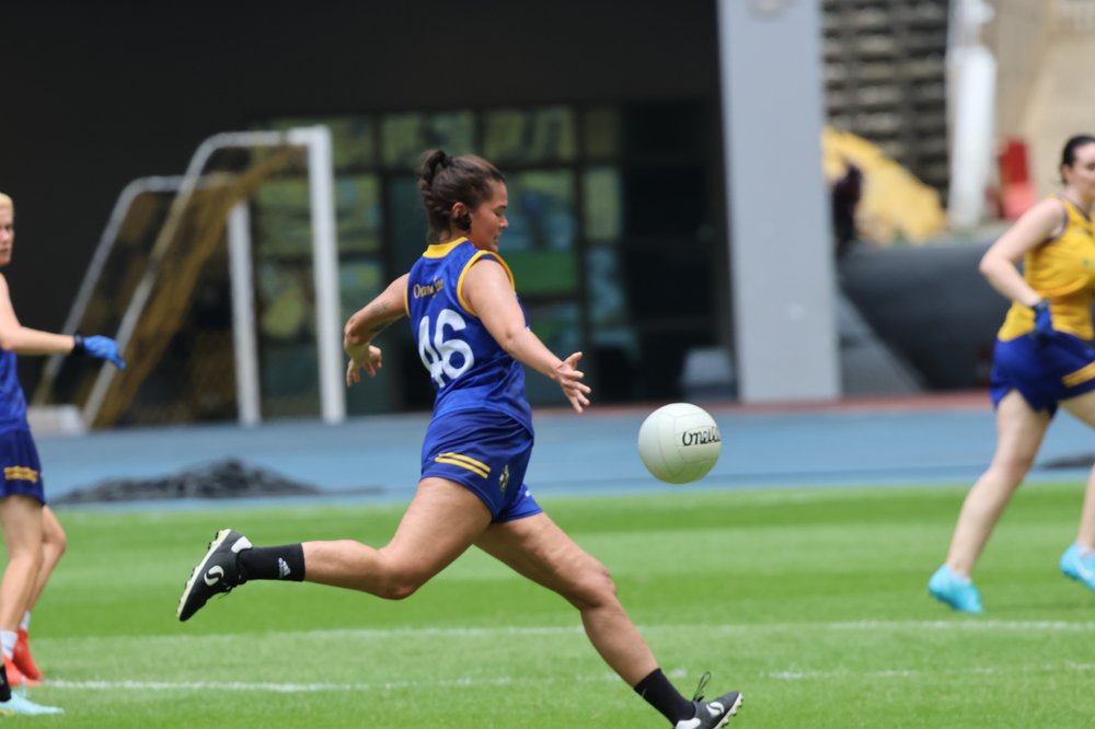 woman in Orang Éire kit kicking a football