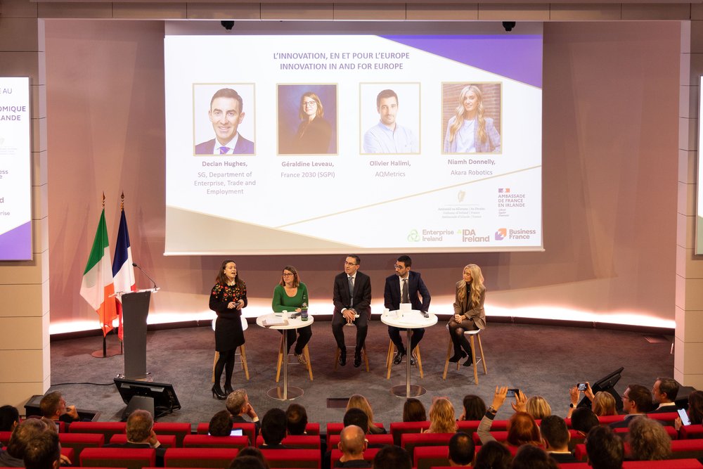 Panel of people on a stage with a screen in the background