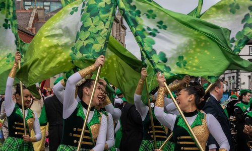 Marching band waving shamrock flags in St Patrick’s Day parade