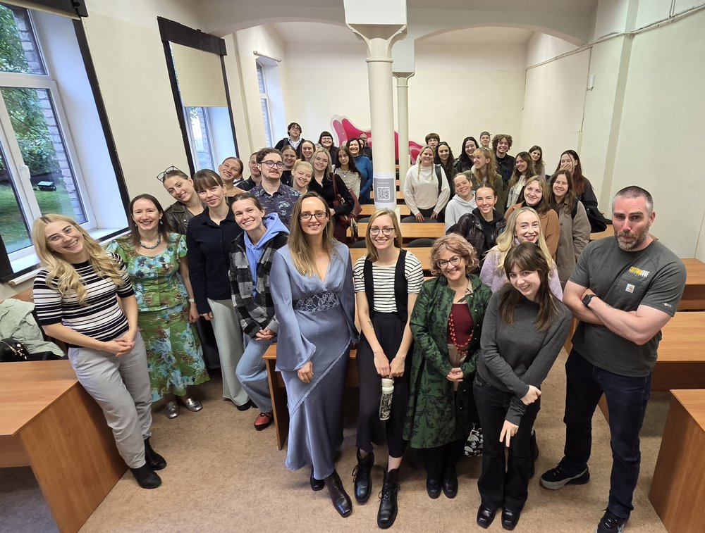 Group of people in a classroom laughing and posing for the camera