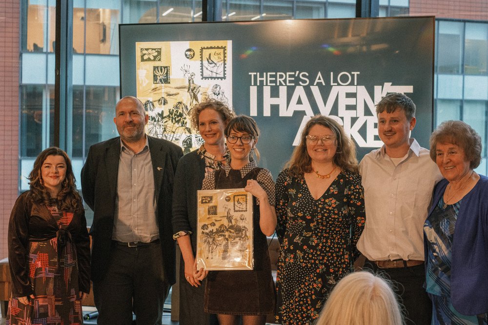 Group of people standing infront of a crowd and a podcast poster