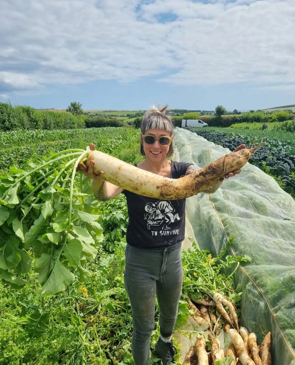 Woman standing in a field holding large freshly picked produce.