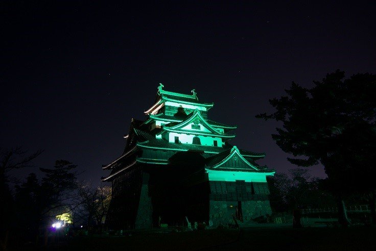 A traditional Japanese building illuminated with green lighting for St. Patrick's Day