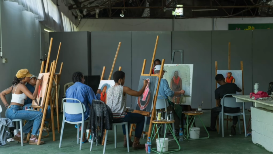 A group of people painting portraits on easels in a class.