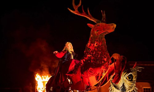 Woman in Celtic dress on a wooden deer sculpture