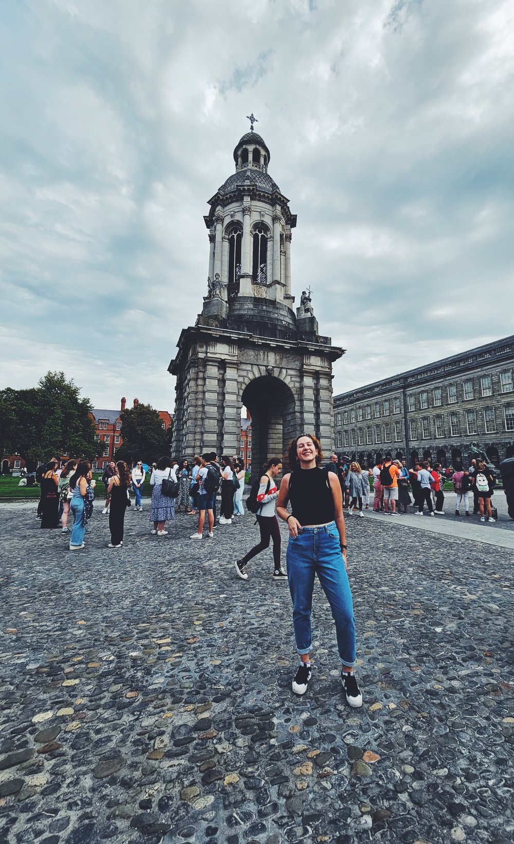 A woman standing in Trinity College front square in front of the Campinile