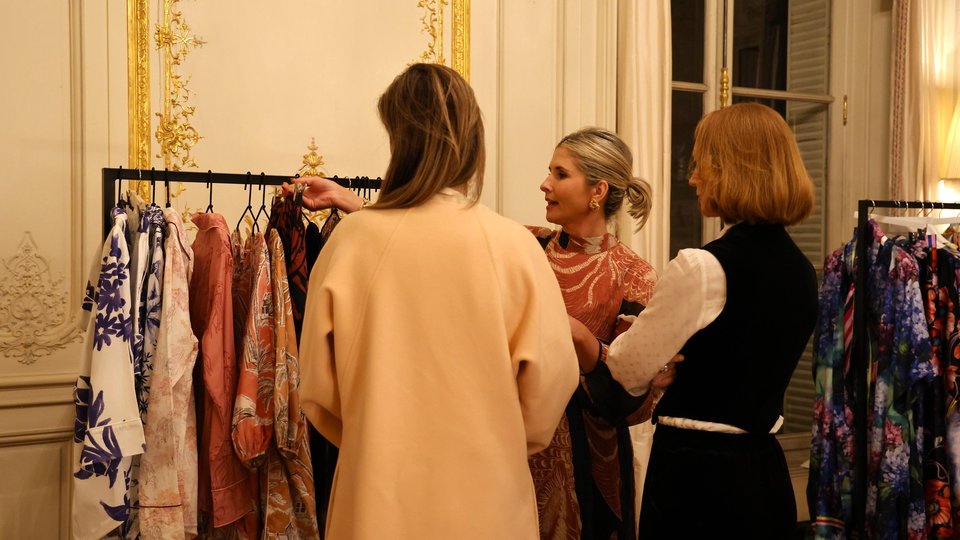 Three women looking at clothing on a rack
