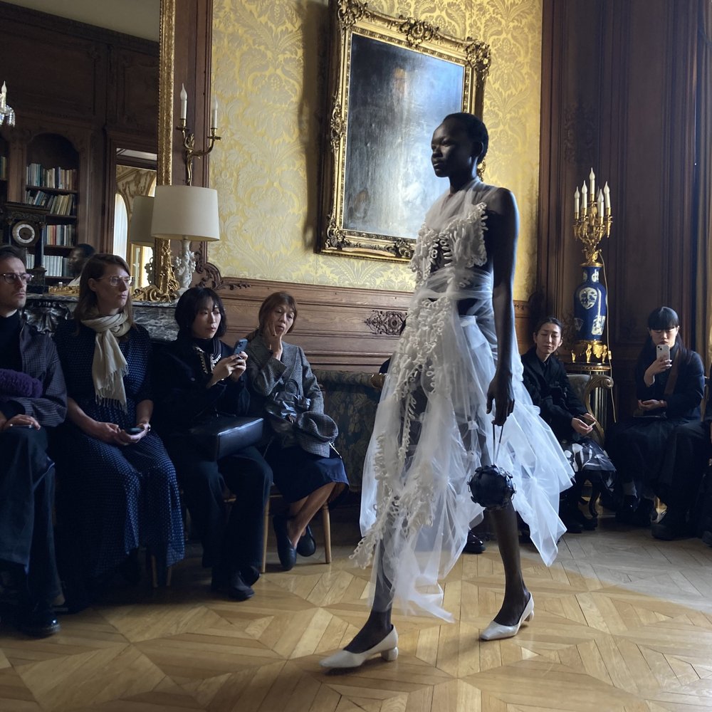 Female model walking in runway show with audience