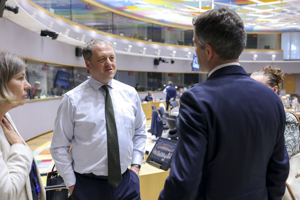 Minister Byrne stands in the Council meeting room speaking to his Dutch counterpart. They stand facing each other. The meeting room and interpretation boxes are visible in the background.