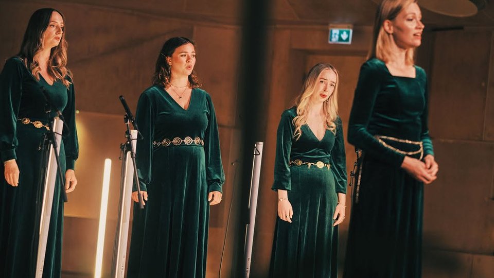 Choir of women singing in green dresses