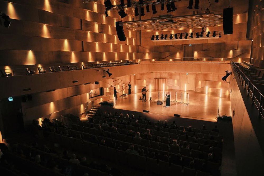 Female choir in long green dresses on stage in a theatre