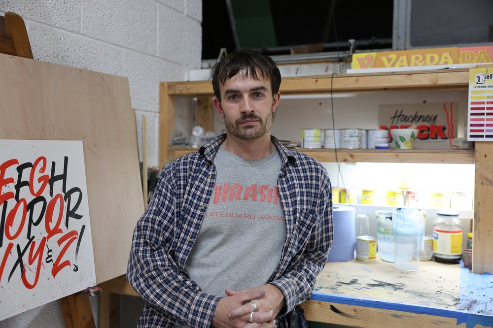 Lockie standing at his desk in his studio