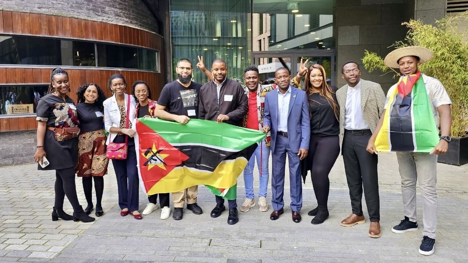 Mozambique fellows standing outside a building holding the Mozambique flag