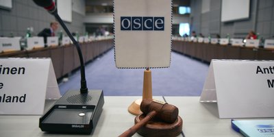 A gavel in front of an OSCE flag at a meeting