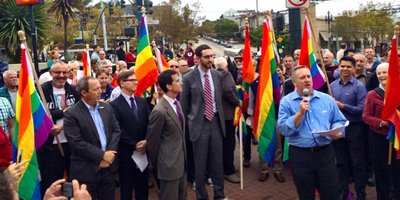 Group of people holding rainbow flags announcing the Honour Walk