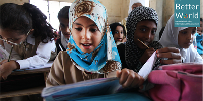 Girls writing in school books at desks.