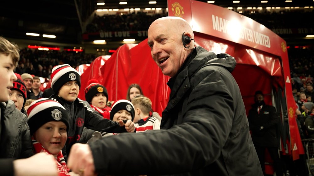 Man talking to a crowd of kids in a stadium