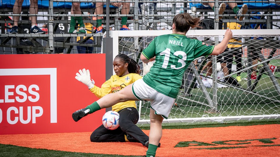 Irish footballer shoots ball towards goal at Homeless World Cup 2024