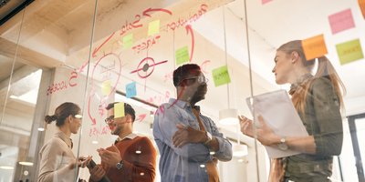 people talking behind a glass with notes and post its at it at a meeting