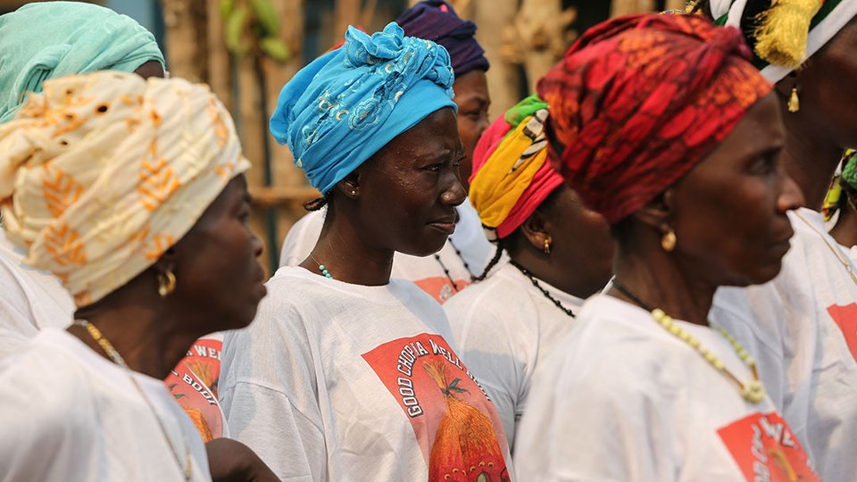 Three African women with different coloured hair scarves and white tshirts