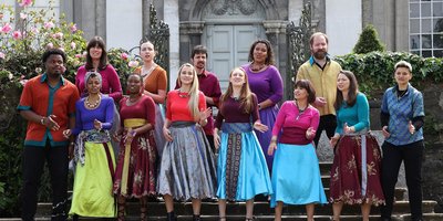 Group of men and women from lots of different backgrounds dressed in colourful costumes and singing