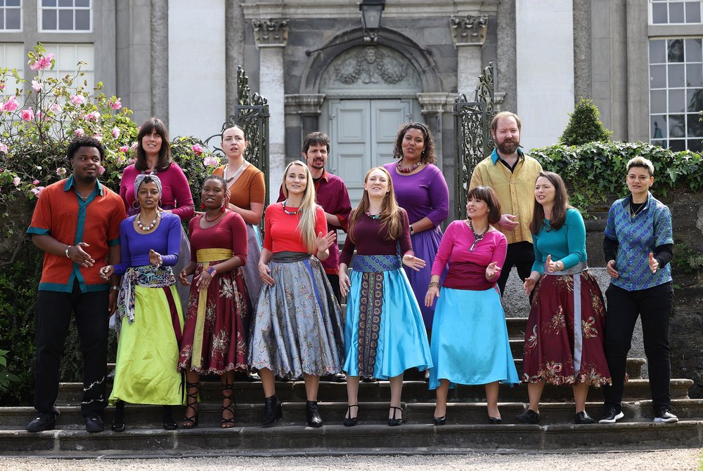 Group of men and women from lots of different backgrounds dressed in colourful costumes and singing