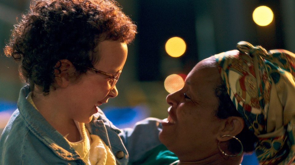 Still from Ama Gloria film, showing a child and mother laughing together