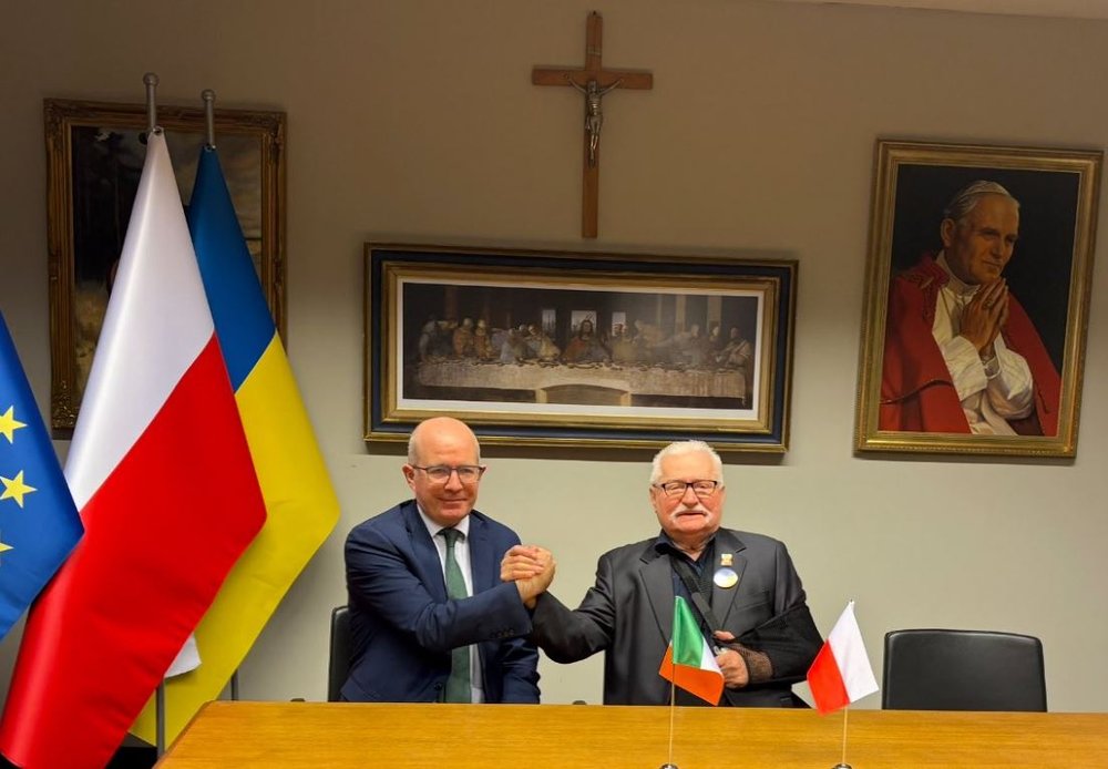 Ambassador Haughey sits beside and shakes hands with Lech Walesa