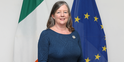 Ambassador Wendy Dorman-Smith standing in front of the Croatian flag.
