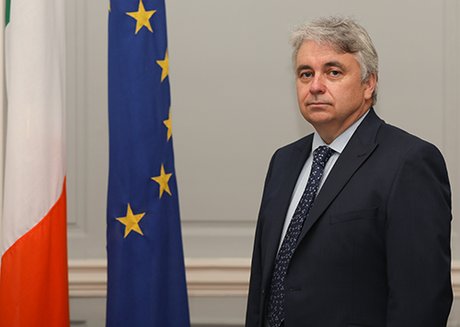 Man standing beside an EU flag and Irish flag