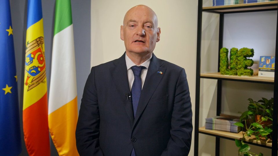Man standing beside an EU flag and Irish flag
