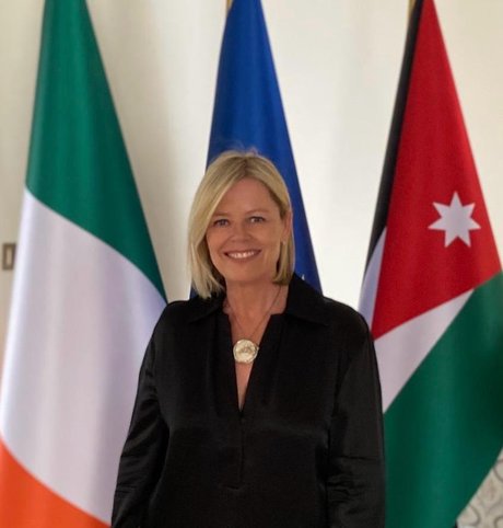Ambassador McHugh standing in front of Irish, EU and Jordanian flags.