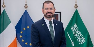 Headshot of Gerry Cunningham in front of the Irish and EU flags.