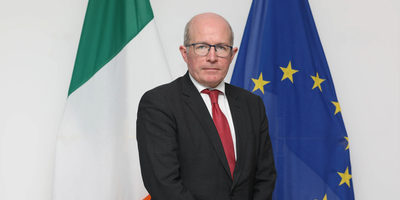 Patrick Haughey headshot in front of Irish and EU flags.