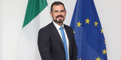 Micheál Smith headshot in front of the Irish and EU flags.