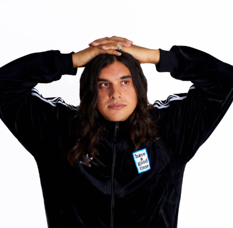 Arveen with his fingers interlocked on top of his head. He is wearing a tracksuit jacket