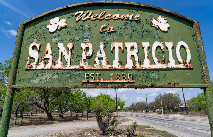 An rusty welcome sign at the entrance to a town