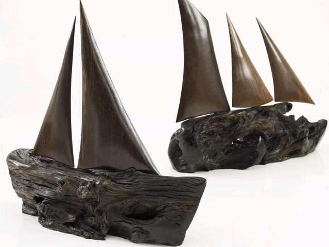 Sculptures of sailboats using bog oak. The artist left the uneven natural form for the body of the boat, and refined the wood for smooth shining sails.