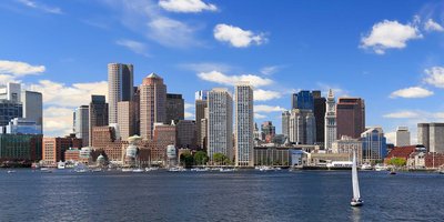 Boston's cityscape skyline viewed from the bay, with high rise buildings on a sunny day.