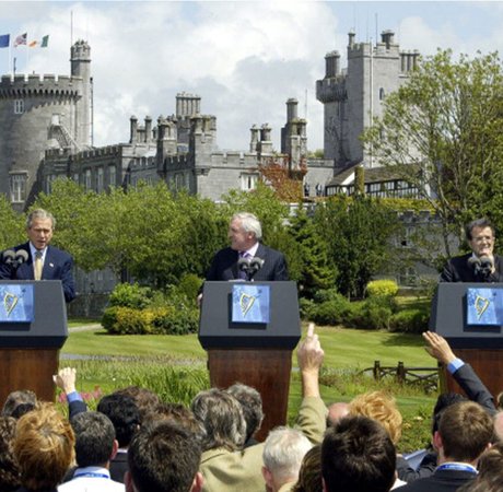 three men at podiums in front of a castle