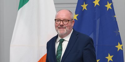 Consul General Brian Cahalane standing in front of the Irish and EU flags.