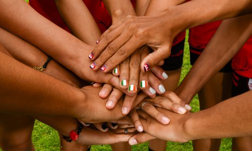 Hands on top of each other, some nails are painted with the Irish flag, others with the Cambodian flag