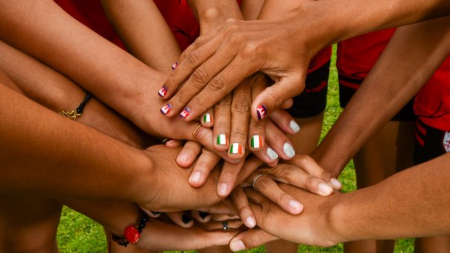Hands on top of each other, some nails are painted with the Irish flag, others with the Cambodian flag