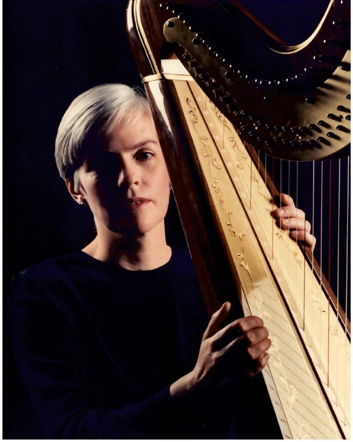 Caitríona Yeats holding a harp in a dark room