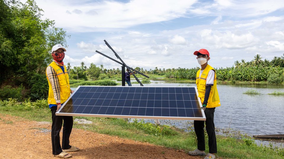 Two people carrying a solar panel
