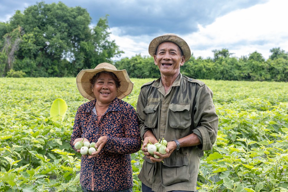 Two people holding produce in a field