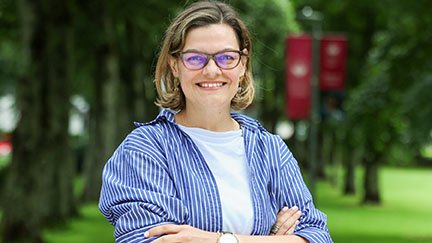 woman outside in front of trees smiling for camera