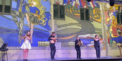 four people singing and play irish music on stage